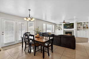Dining space with built in shelves, light tile patterned floors, a tiled fireplace, a chandelier, and a textured ceiling
