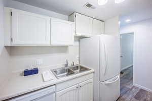 Kitchen with white cabinets, light countertops, white appliances, dark wood-style floors, and recessed lighting