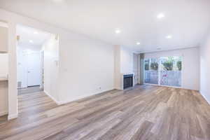 Unfurnished living room with light wood-type flooring, recessed lighting, and a fireplace