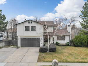 View of front of property with stucco siding, a garage, a chimney, and concrete driveway