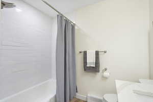Bathroom with shower / bath combination with curtain, vanity, and baseboard heating