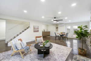 Living room with finished concrete floors, ceiling fan, recessed lighting, built in features, and baseboard heating