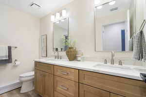 Full bath featuring double vanity and light wood-style floors