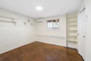 Empty room featuring brick wall, concrete floors, and a mini split for heating / cooling