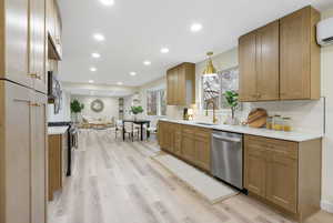 Kitchen with open floor plan, stainless steel appliances, light wood-style floors, and light stone counters