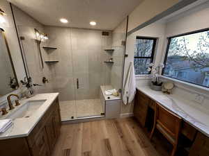 Bathroom featuring light wood-style flooring, a stall shower, vanity, a textured ceiling, and recessed lighting