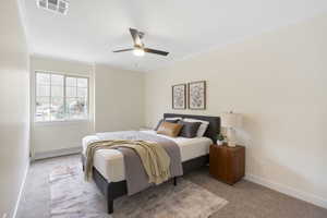 Carpeted bedroom featuring a baseboard heating unit, crown molding, and a ceiling fan
