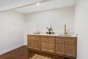 Bar area with wood finish cabinets, concrete flooring, and light stone countertops