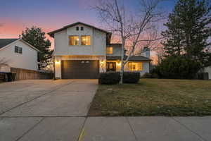 View of front of property featuring an attached garage, driveway, and stucco siding