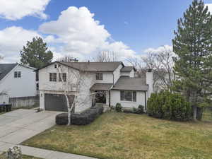 Traditional-style house featuring a chimney, a garage, driveway, roof with shingles, and stucco siding