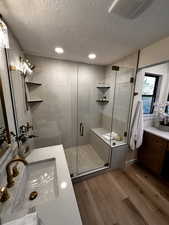 Full bathroom with vanity, dark wood finished floors, a stall shower, a textured ceiling, and recessed lighting