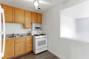 Kitchen featuring white appliances, light countertops, dark wood-style flooring, a ceiling fan, and light wood finish cabinetry