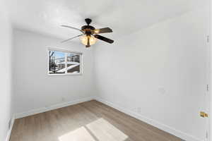 Empty room with a ceiling fan and light wood-type flooring