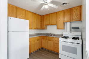 Kitchen featuring white appliances, light countertops, ceiling fan, a textured ceiling, and light wood-type flooring