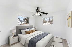 Bedroom with light wood-style flooring, multiple windows, and ceiling fan
