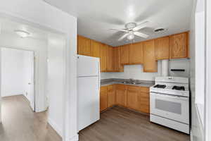 Kitchen featuring white appliances, light countertops, light wood-type flooring, and ceiling fan