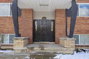 Snow covered property entrance featuring brick siding