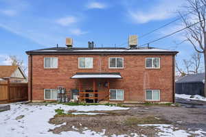 Snow covered rear of property featuring brick siding