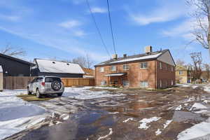Snow covered back of property featuring brick siding