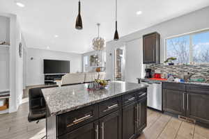 Kitchen with dark stone counters, tasteful backsplash, wood tiled floors, and stainless steel dishwasher