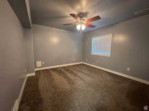 Unfurnished room with dark colored carpet and ceiling fan