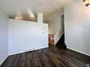 Unfurnished living room featuring dark wood finished floors and stairway
