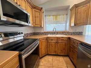 Kitchen featuring stainless steel appliances, light countertops, wood finish cabinets, and lofted ceiling