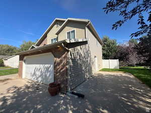 View of property exterior with a garage, brick siding, stucco siding, and driveway