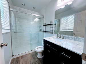 Bathroom with vanity, a stall shower, and dark wood-type flooring