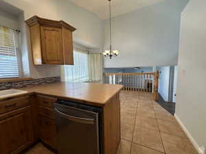 Kitchen with dishwasher, lofted ceiling, light tile patterned floors, a peninsula, and suspended lighting