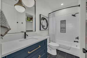 Bathroom featuring vanity, shower / tub combo, dark tile patterned floors, and recessed lighting