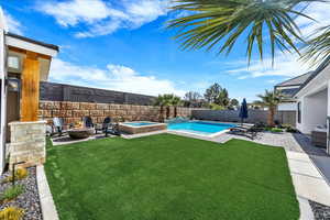 Fenced backyard featuring a patio area, a pool with connected hot tub, and a fire pit