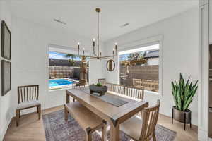 Dining area with light wood finished floors, suspended lighting, and brick wall