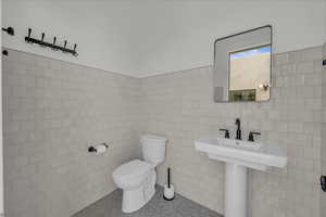 Half bath with tile walls and speckle patterned floor