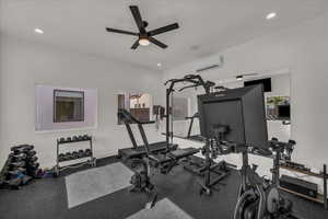 Exercise area featuring rubber floors, a ceiling fan, and a wall mounted mini split