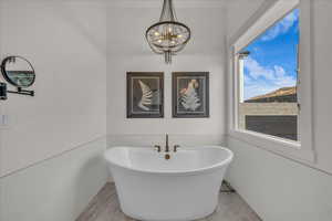 Full bath with a freestanding bath, hanging lights, and tile walls