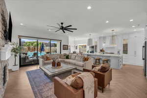 Living area featuring parquet floors, healthy amount of natural light, a stone fireplace, and a ceiling fan
