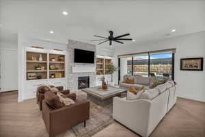 Living room with parquet floors, ceiling fan, a stone fireplace, and recessed lighting