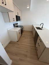 Dual tone kitchen with light stone countertops, stainless steel appliances, a peninsula, light wood-style floors, and modern cabinets