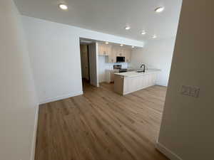 Kitchen with light countertops, a peninsula, light wood-style floors, stainless steel appliances, and open floor plan