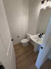 Half bathroom featuring dark wood-style floors and toilet