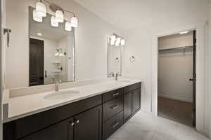 Bathroom with a walk in closet, double vanity, a shower stall, and light marble finish floors