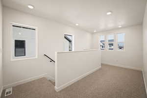 Hallway featuring an upstairs landing, light carpet, and recessed lighting