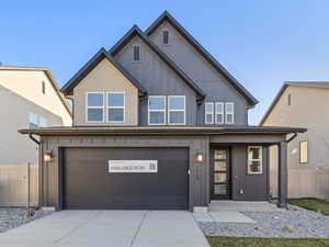 View of front of home featuring driveway, a garage, a porch, and board and batten siding