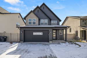 View of front of house with a garage, board and batten siding, covered porch, and stucco siding