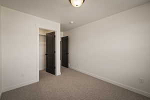 Unfurnished bedroom featuring a walk in closet, carpet flooring, and a textured ceiling