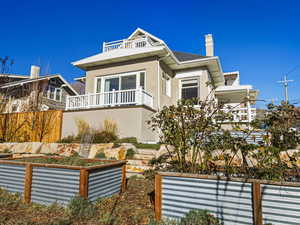 View of front facade with a balcony, a chimney, and stucco siding