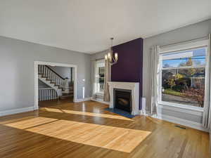 Unfurnished living room with a chandelier, light wood finished floors, and a fireplace with flush hearth