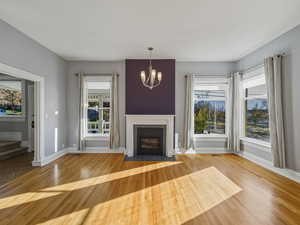 Unfurnished living room with suspended lighting, light wood-style floors, and a tiled fireplace
