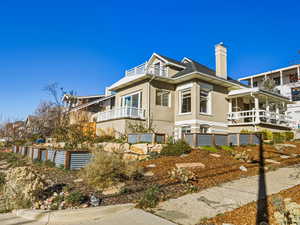 View of side of property with stucco siding, a balcony, and a chimney